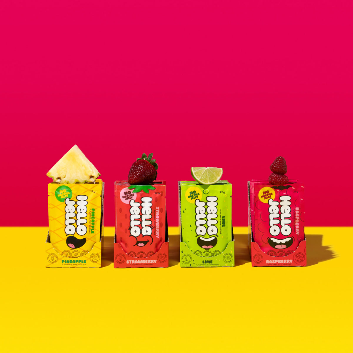 Four HELLO JELLO sachets standing with fresh fruit, one of each flavour
