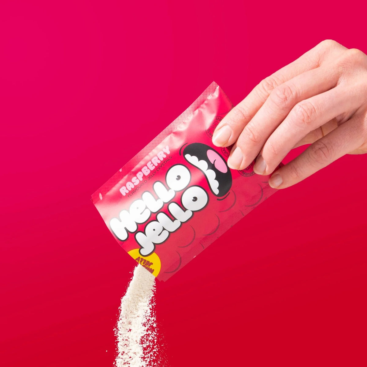 Pouring HELLO JELLO Raspberry jelly crystals from the sachet
